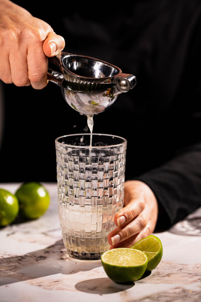 Fresh lime being squeezed into the margarita.