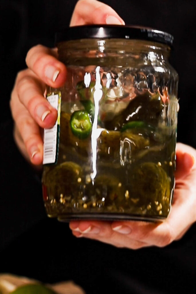 Hands shaking margarita in a pickle jar.