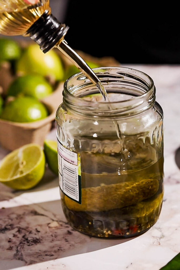 Agave syrup being added to a pickle margarita.