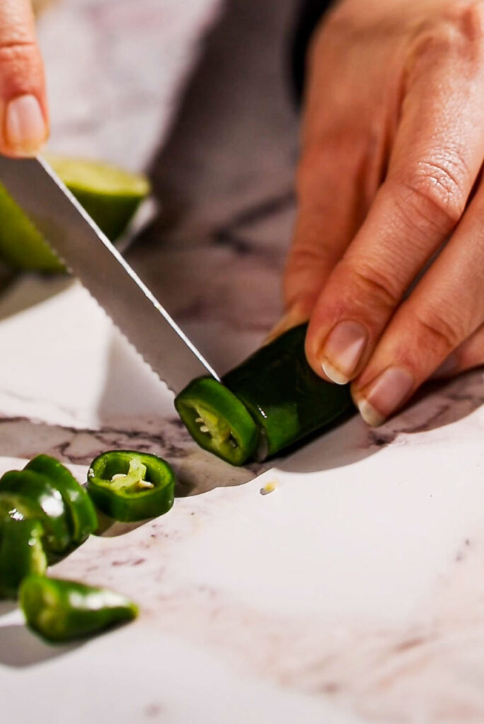 Knife slicing jalapeños.