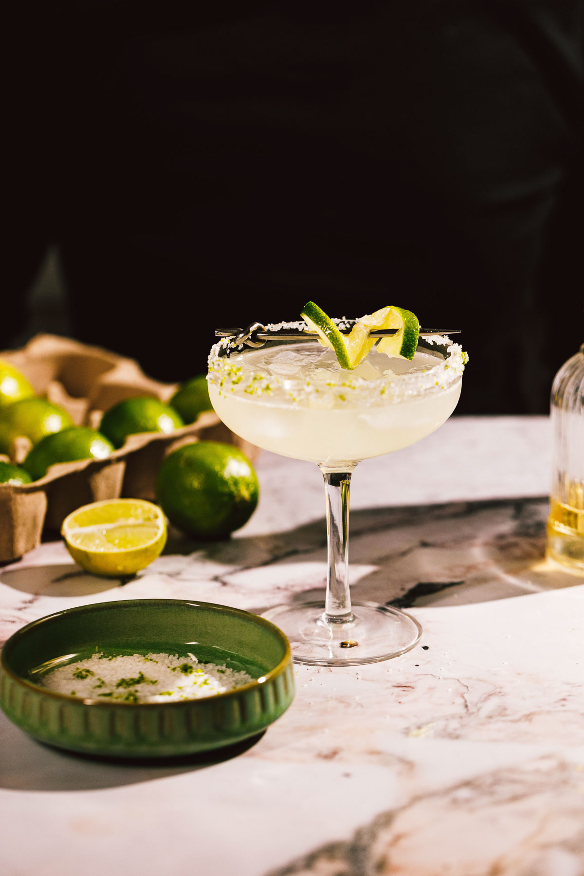 Side shot showing a coupe glass filled with an ice cold margarita made with mezcal.