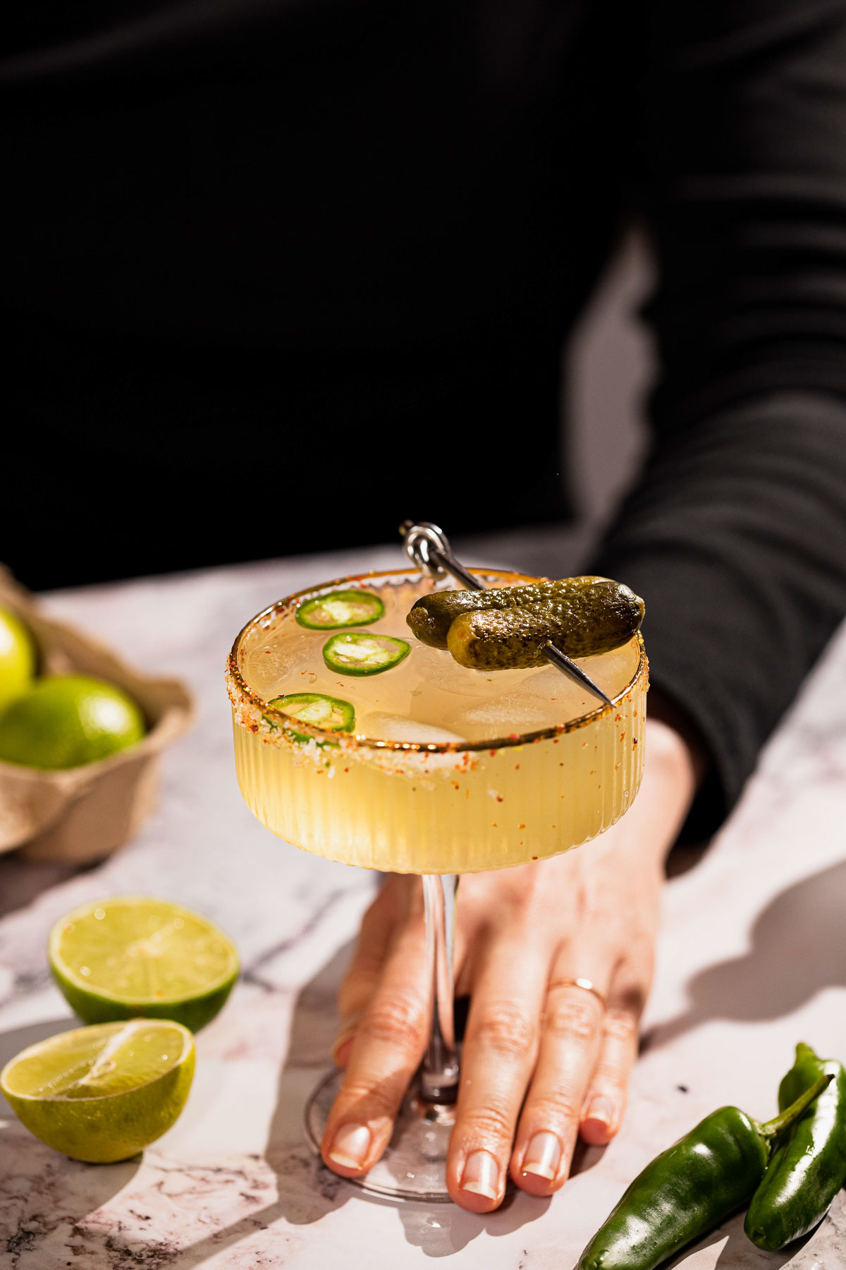 Hand sliding spicy pickle margarita forward.