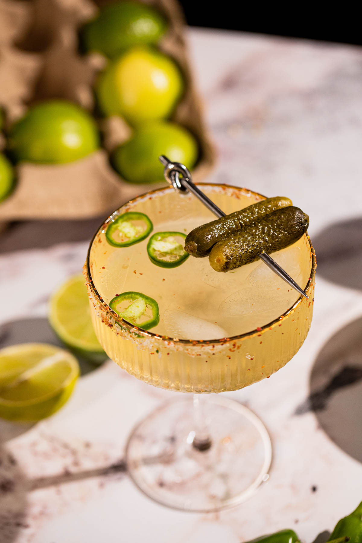 close up of a pickle margarita garnished with gherkins on a cocktail pick.